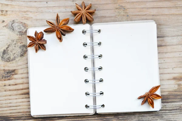 Un cuaderno en espiral retro vacío con viejas estrellas de papel y anís sobre una mesa de madera — Foto de Stock