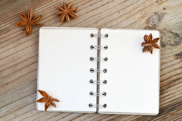 Un cuaderno en espiral retro vacío con viejas estrellas de papel y anís sobre una mesa de madera — Foto de Stock