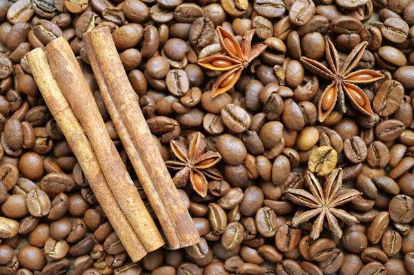 Spicy anise stars and cinnamon sticks on lots of roasted coffee beans — Stock Photo, Image