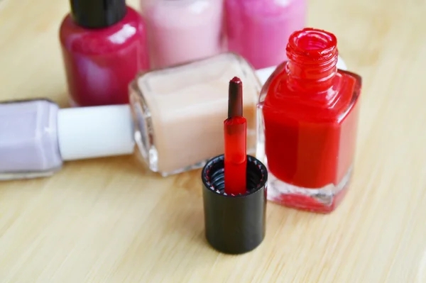 Ένα μπουκάλι κόκκινο βερνίκι νυχιών με άλλα πολύχρωμα μπουκάλια closeup — Φωτογραφία Αρχείου