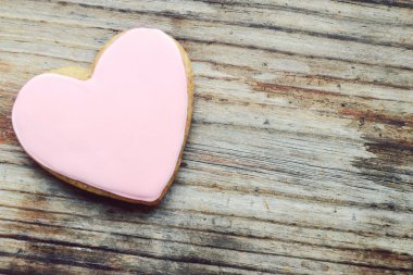 Ahşap masa üzerine pembe krema ile kalp şeklinde gingerbread