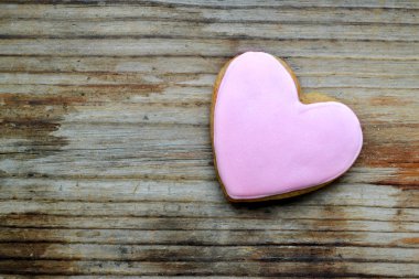 Ahşap masa üzerine pembe krema ile kalp şeklinde gingerbread