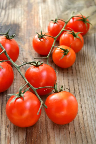 Куча маленьких красных помидоров черри на деревянном столе — стоковое фото
