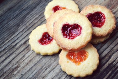 Ahşap masa üzerinde kalp şeklinde reçelli ev yapımı kurabiye