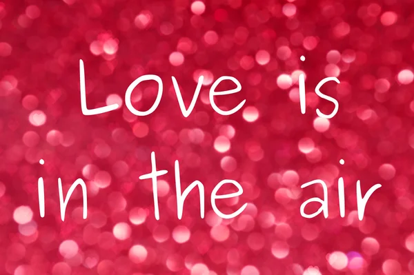 Love Is In The Air bericht over heldere en abstracte wazig roze achtergrond met glinsterende glitter — Stockfoto