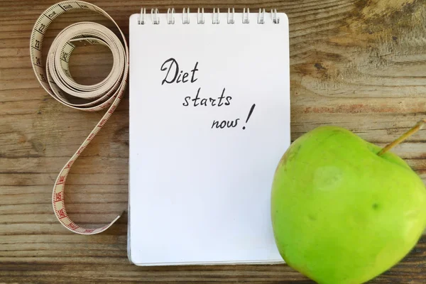 Pojęcie diety z zielonym jabłkiem, notatnik i miarkę na drewnianym stole — Zdjęcie stockowe