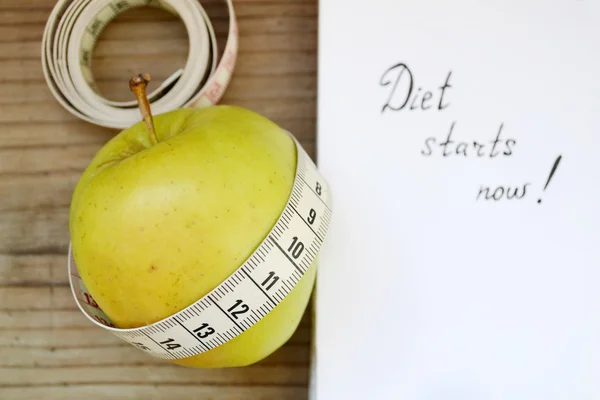 Diet concept with green apple, a notebook and a measuring tape on wooden table — Stock Photo, Image