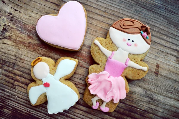 Pão de gengibre em forma de coração e anjo com gelo rosa e branco e pequeno dançarino de balé bonito na mesa de madeira — Fotografia de Stock