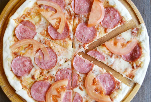 Большая горячая пицца с помидорами и салями — стоковое фото