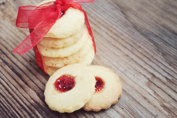 Galletas de mermelada caseras con lazo de cinta roja en mesa de madera — Foto de Stock