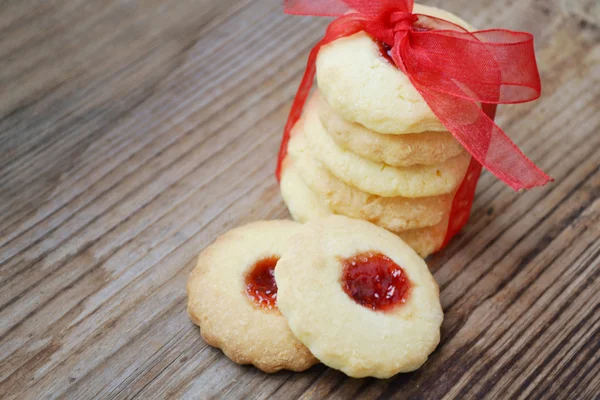 Homemade jam cookies with red ribbon bow on wooden table — Stock Photo, Image