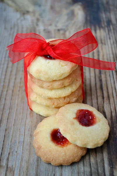 Homemade jam cookies with red ribbon bow on wooden table — Stock Photo, Image