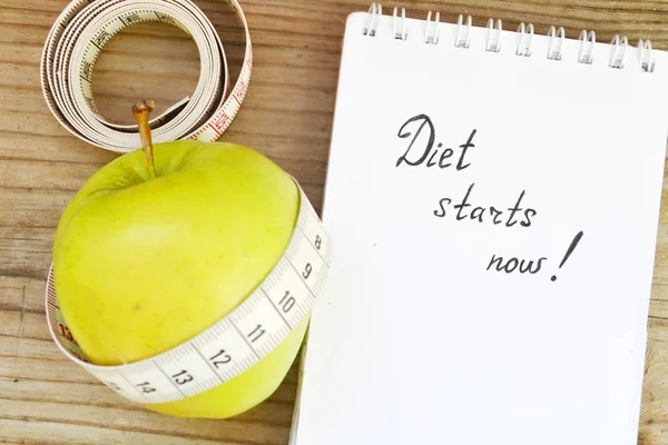 Diet concept with green apple, a notebook and a measuring tape on wooden table — Stock Photo, Image