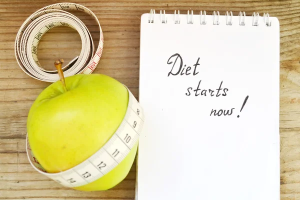 Conceito de dieta com maçã verde, um caderno e uma fita métrica na mesa de madeira — Fotografia de Stock