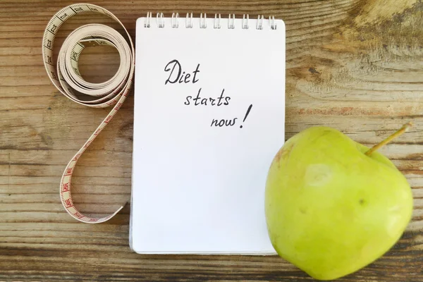 Conceito de dieta com maçã verde, um caderno e uma fita métrica na mesa de madeira — Fotografia de Stock