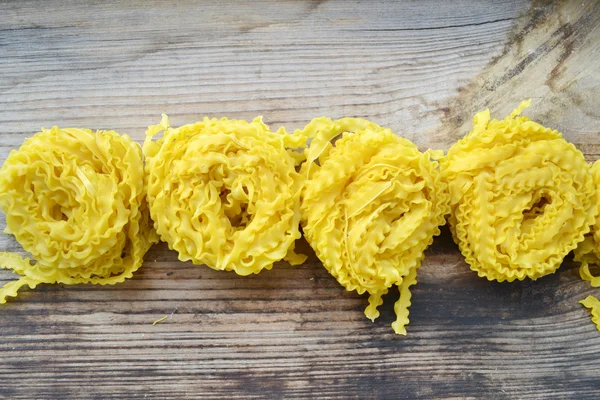 Rå pasta Reginette (Mafaldine) på träbord — Stockfoto