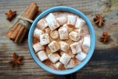 Sıcak kakao marshmallows, yıldız anason ve tarçın ile siyah ve mavi bir fincan