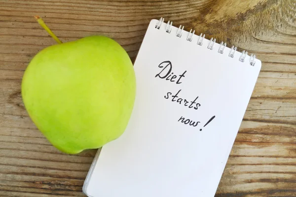 Conceito de dieta com maçã verde, um caderno e uma fita métrica na mesa de madeira — Fotografia de Stock