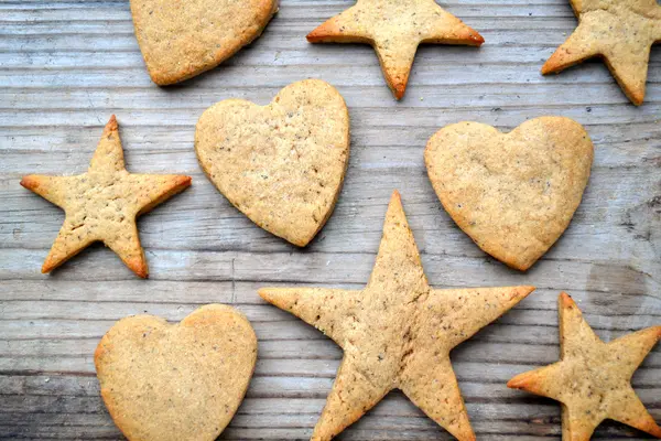 Galletas de jengibre en forma de corazón y estrella sobre mesa de madera — Foto de Stock