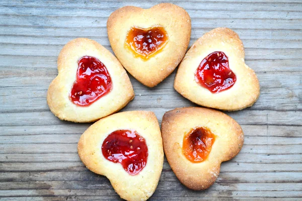 Biscoitos caseiros com geléia em forma de coração na mesa de madeira — Fotografia de Stock