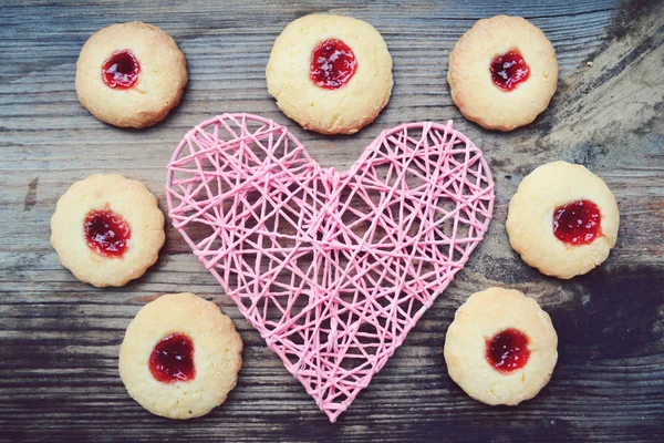 Ρομαντική έννοια με χειροποίητα ροζ καρδιά και πολλά σπιτικά μπισκότα με μαρμελάδα σε ξύλινο τραπέζι — Φωτογραφία Αρχείου