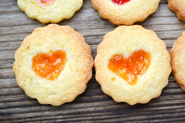 Galletas caseras con mermelada en forma de corazón en mesa de madera — Foto de Stock