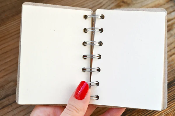 Hermosa mano de mujer con clavos rojos sosteniendo un cuaderno de espiral retro vacío con papel viejo —  Fotos de Stock