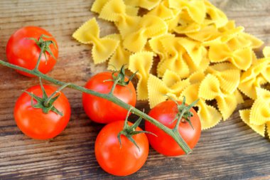 Küçük kırmızı kiraz domates ve kelebek makarna farfalle ahşap tablo şeklinde