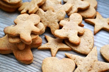 Gingerbread çerezleri şekillerdeki kalp, yıldız ve kabuk tarçın ve zencefil kökü ahşap masa üzerinde olan adam