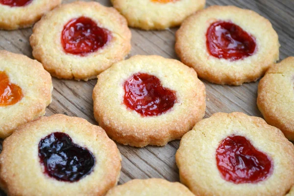 Biscoitos caseiros com geléia em forma de coração na mesa de madeira — Fotografia de Stock