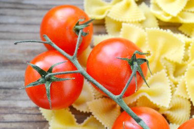Küçük kırmızı kiraz domates ve kelebek makarna farfalle ahşap tablo şeklinde