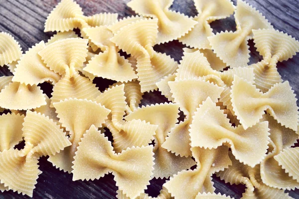 Borboleta não cozida em forma de macarrão farfalle na mesa de madeira — Fotografia de Stock