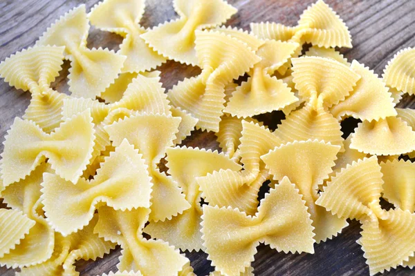 Borboleta não cozida em forma de macarrão farfalle na mesa de madeira — Fotografia de Stock