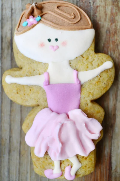 Gingerbread in a shape of heart and angel with pink and white icing and little cute ballet dancer on wooden table — Stock Photo, Image