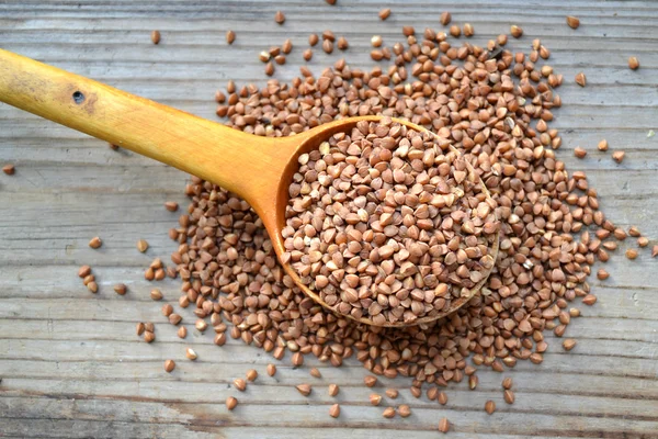 Buckwheat grains with an old big spoon on wooden table — Stock Photo, Image