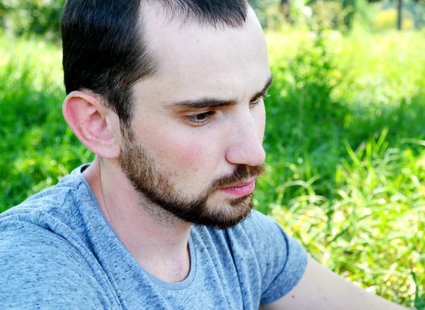 Young man with beard looking thoughtfully and smiling — Stock Photo, Image