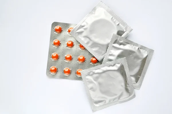 Три презервативи і таблетки контролю народжуваності ізольовані на білому — стокове фото