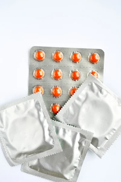 Three condoms and birth control pills isolated on white — Stock Photo, Image