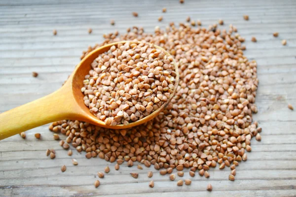 Buckwheat grains with an old big spoon on wooden table — Stock Photo, Image
