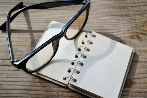 Prázdné retro spirála notebook s starý papír a brýle na čtení — Stock fotografie