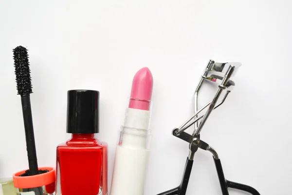 Kosmetyki z tusz do rzęs czarny, różowy i czerwony lakier do paznokci i szminka i rzęs curlerka na białym tle — Zdjęcie stockowe