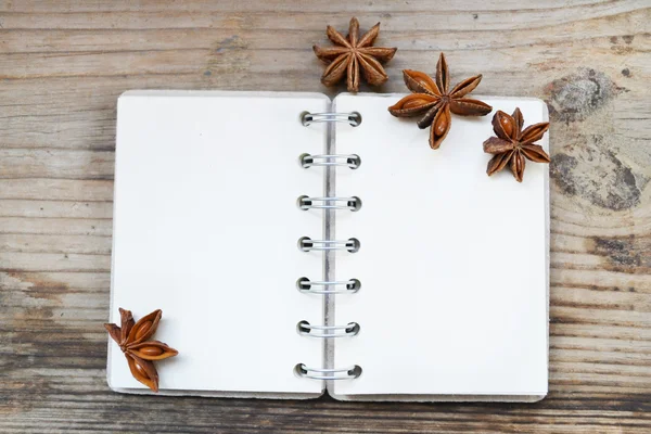 Un cuaderno en espiral retro vacío con viejas estrellas de papel y anís sobre una mesa de madera — Foto de Stock