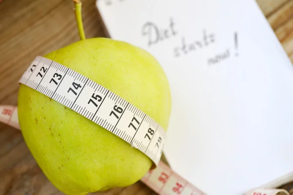 Concepto de dieta con manzana verde, un cuaderno y una cinta métrica en la mesa de madera —  Fotos de Stock