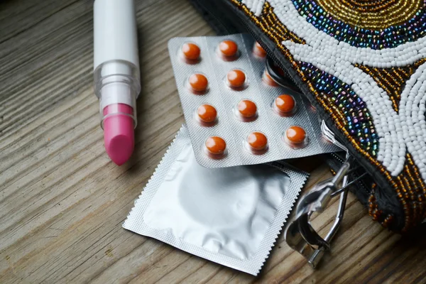 Birkaç prezervatif ve siyah rimel, pembe ve kırmızı oje ve ruj ve kirpik kıvırıcı ayarlamak bir kozmetik — Stok fotoğraf
