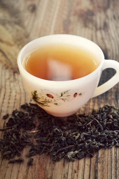 Té de manzanilla en una taza blanca vintage con flores de margarita en la mesa de madera — Foto de Stock