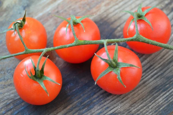 Kilka małych czerwone pomidory na drewnianym stole — Zdjęcie stockowe