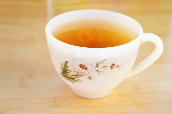 Chá de camomila em uma xícara branca vintage com flores de margarida na mesa de madeira — Fotografia de Stock