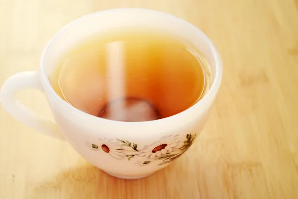 Té de manzanilla en una taza blanca vintage con flores de margarita en la mesa de madera — Foto de Stock