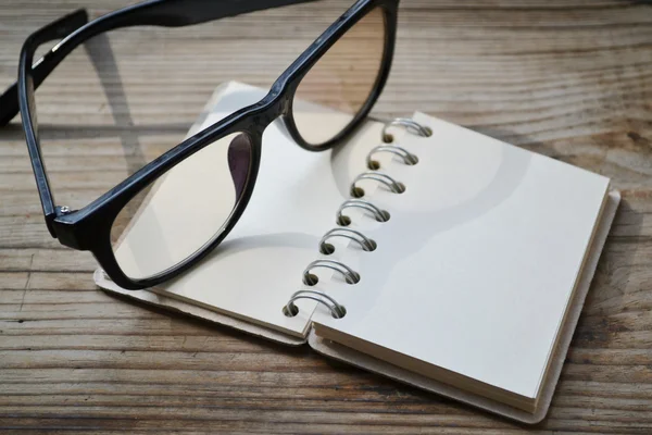 An empty retro spiral notebook with old paper and reading glasses — Stock Photo, Image