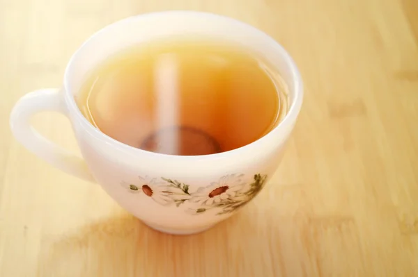 Té de manzanilla en una taza blanca vintage con flores de margarita en la mesa de madera — Foto de Stock